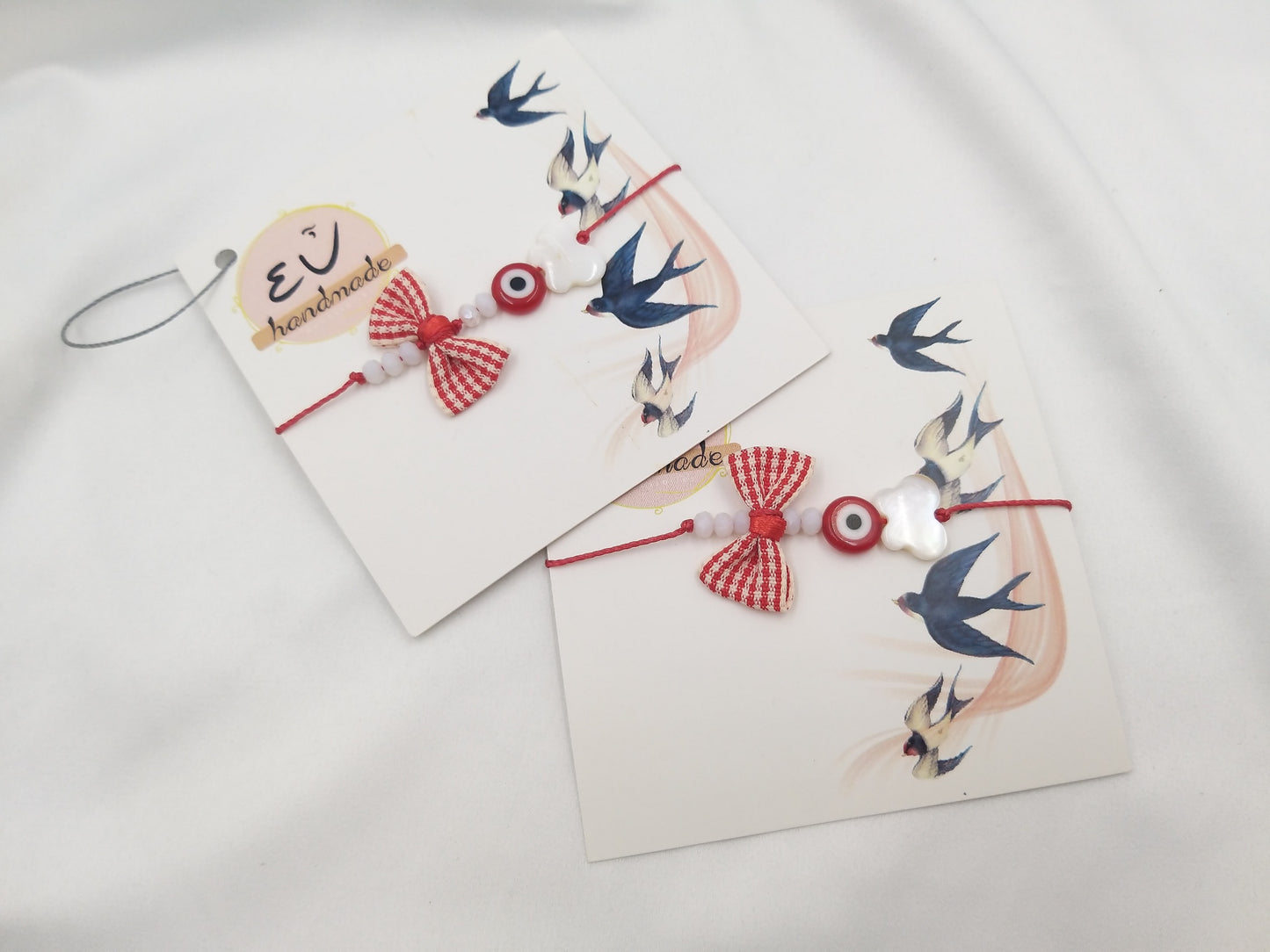 Χειροποίητο μαρτάκι με ριγέ κόκκινο φιόγκο, μάτι και λευκό στοιχείο σε κόκκινο κορδόνι