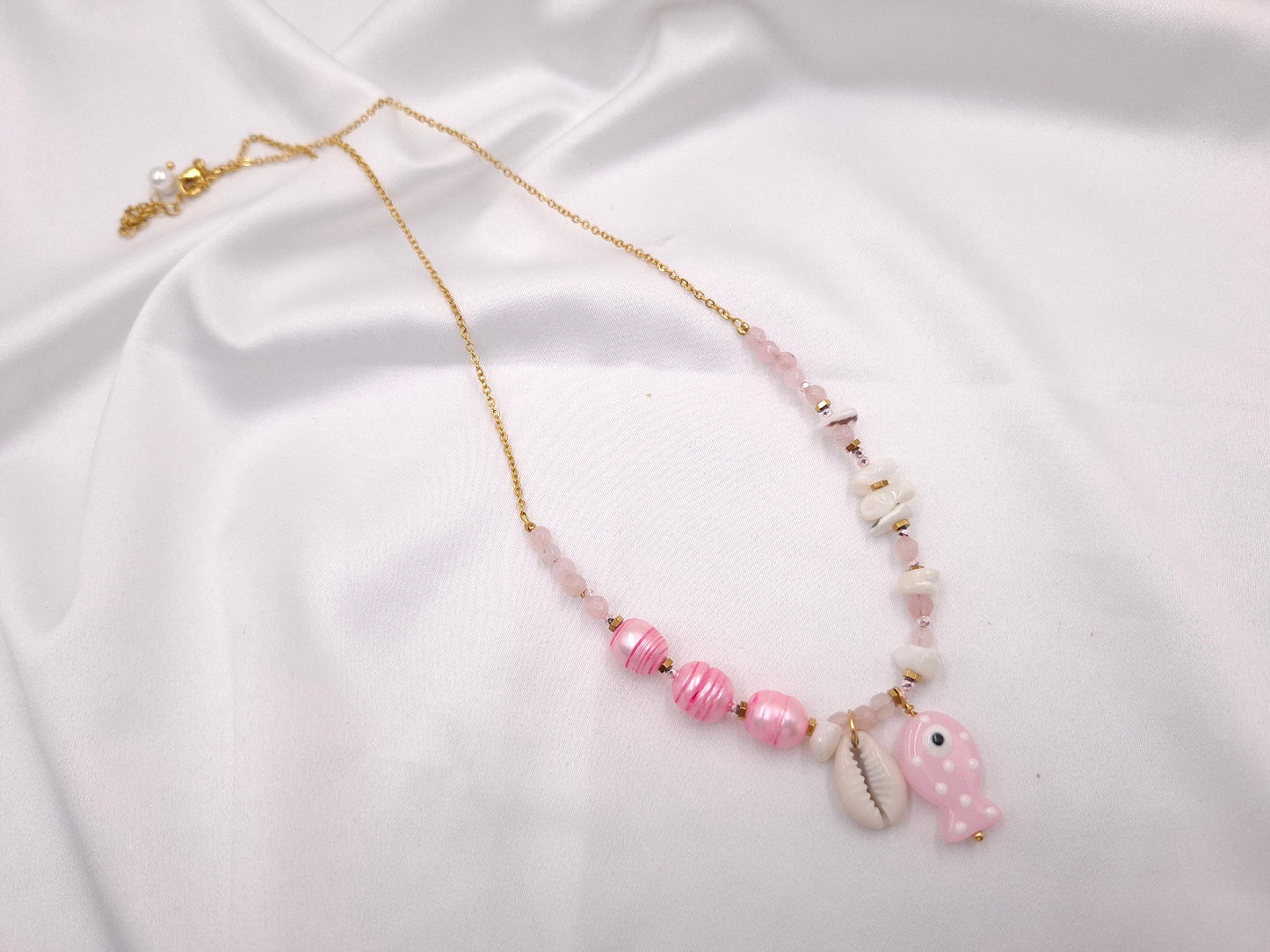 Χειροποίητο κολιέ Fish Tales Pink Shell της euhandmade με ροζ γυάλινες χάντρες, ριγέ ροζ πέρλες, γυάλινο ψαράκι, κοχύλι και χρυσαφί ατσάλινη αλυσίδα.