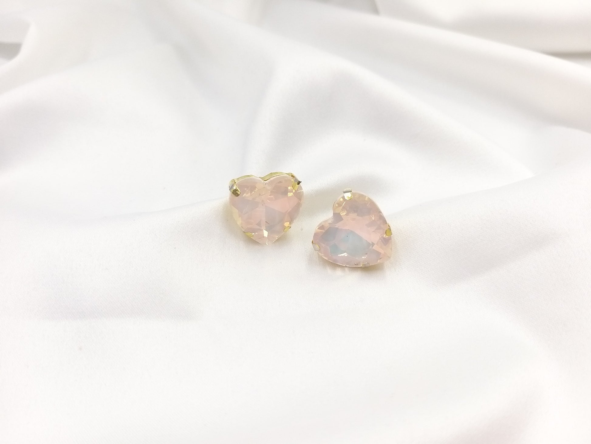 Καρφωτά σκουλαρίκια Drops Heart Studs με απαλή ροζ κρυστάλλινη καρδιά πάνω σε λευκό σατέν