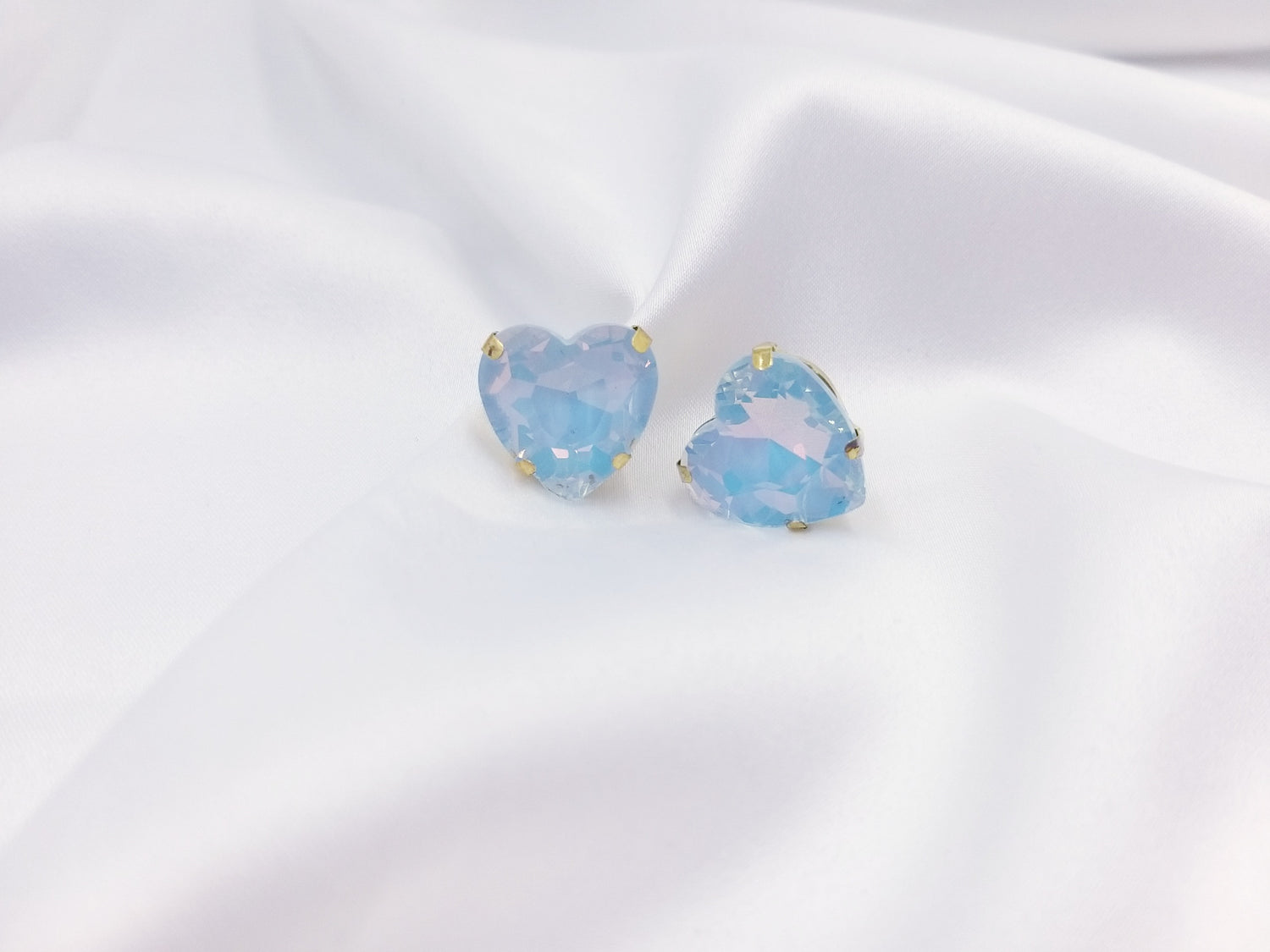 Καρφωτά σκουλαρίκια Drops Heart Studs με γαλάζια κρυστάλλινη καρδιά πάνω σε λευκό σατέν