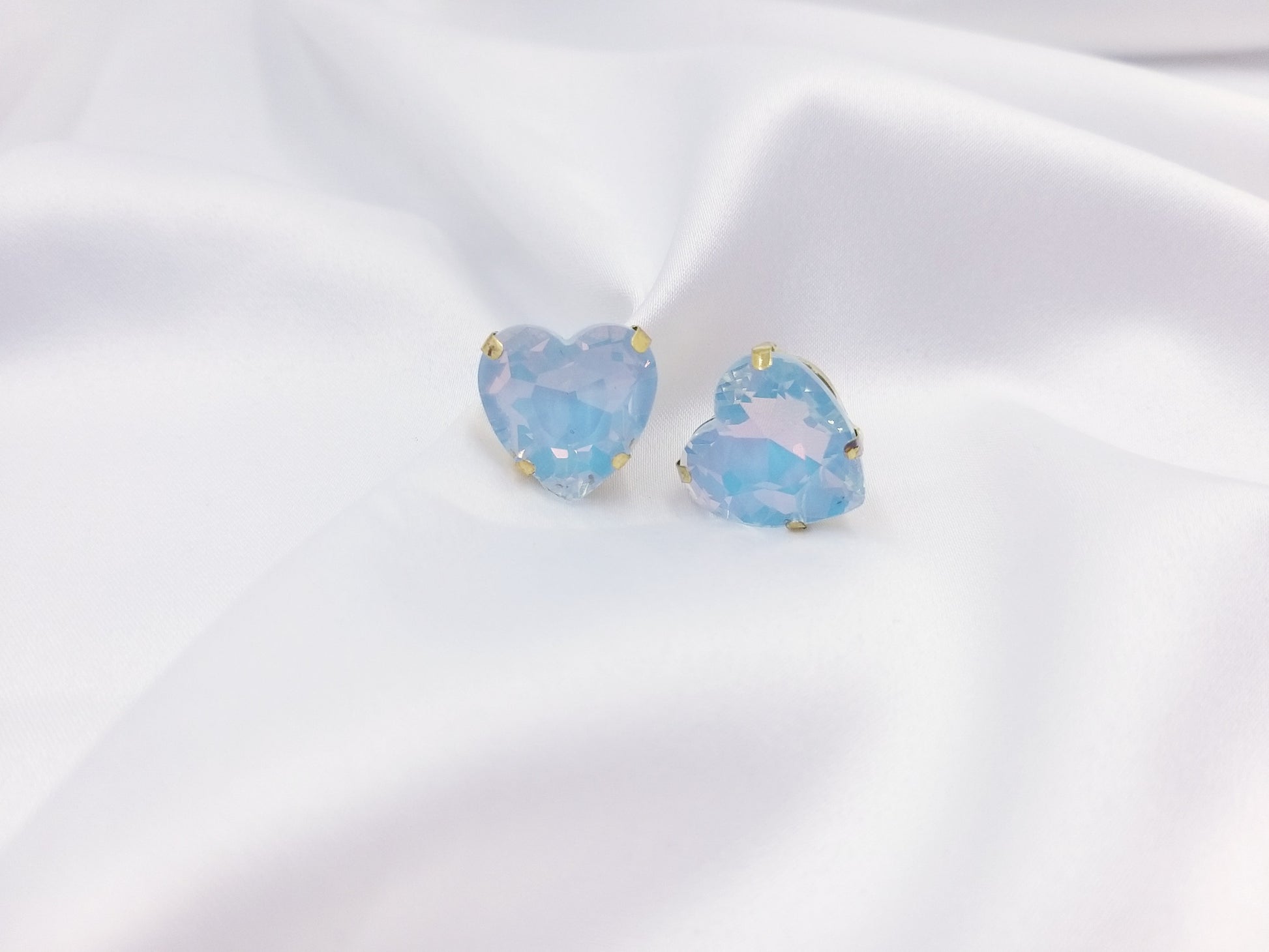 Καρφωτά σκουλαρίκια Drops Heart Studs με γαλάζια κρυστάλλινη καρδιά πάνω σε λευκό σατέν
