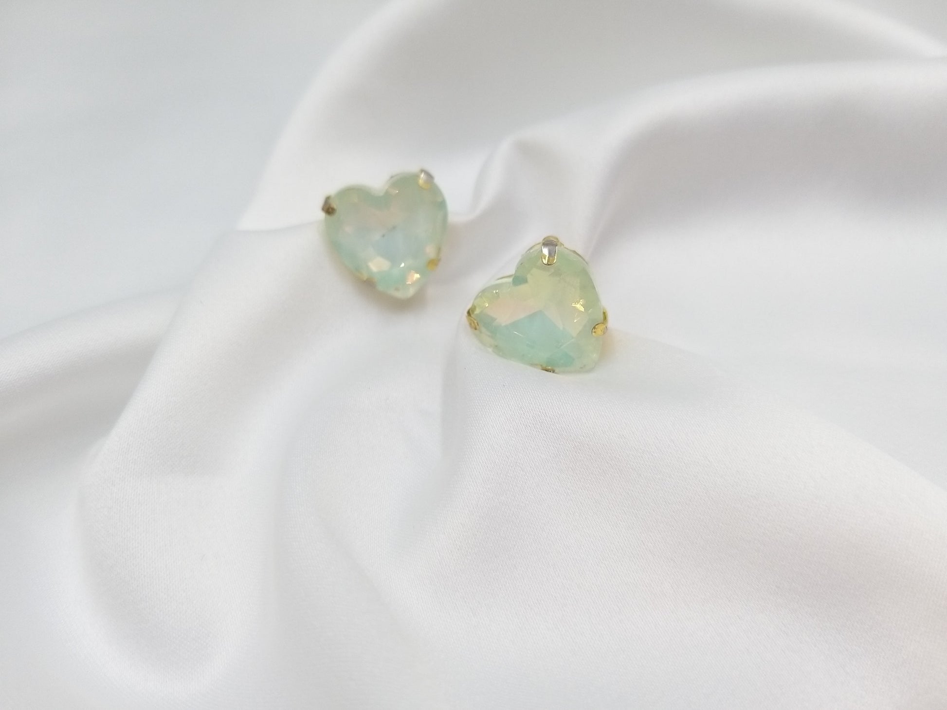 Καρφωτά σκουλαρίκια Drops Heart Studs με μέντα κρυστάλλινη καρδιά πάνω σε λευκό σατέν