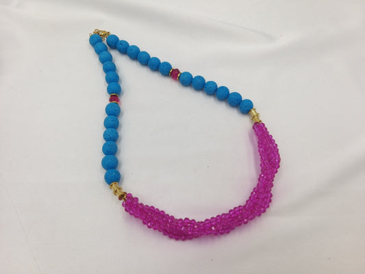 Χειροποίητο κολιέ με σειρές από φούξια κρυστάλλους 4mm και τυρκουάζ πέτρες λάβας, φωτογραφημένο πάνω σε φωτεινό ύφασμα.