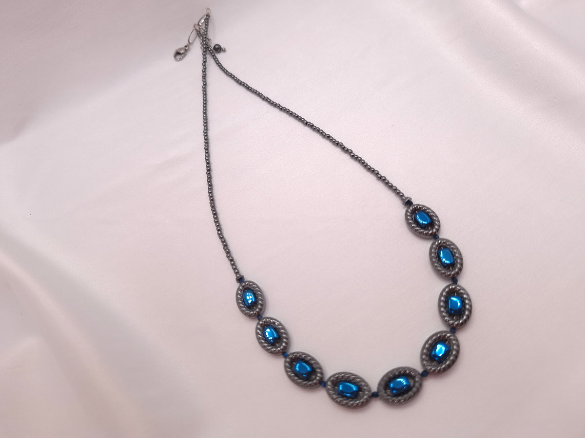 Χειροποίητο κολιέ με εννέα ανάγλυφα οβάλ στοιχεία αιματίτη και έντονες μπλε λεπτομέρειες αιματίτη
