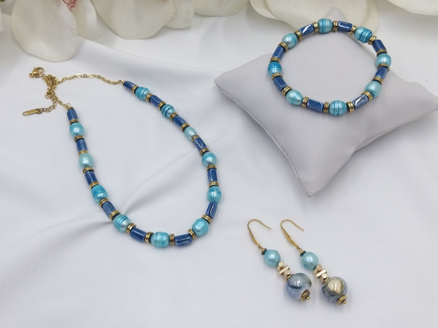 Χειροποίητο σετ κοσμημάτων με μπλε και τιρκουάζ χάντρες – κολιέ, βραχιόλι και σκουλαρίκια με χρυσές λεπτομέρειες.