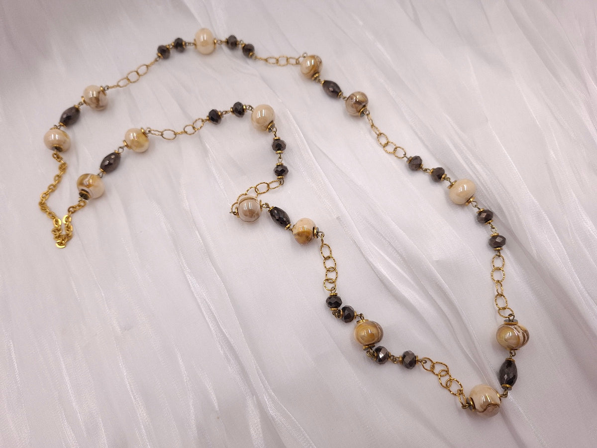 Χειροποίητο μακρύ κολιέ euhandmade με εκρού κεραμικές χάντρες 13mm, κρύσταλλα σε σκούρο μεταλλικό καφέ και χρυσαφί ατσάλινη αλυσίδα.