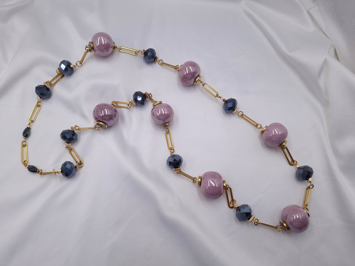 Χειροποίητο μακρύ κολιέ euhandmade με λιλά ιριδίζουσες κεραμικές χάντρες 22mm, ανθρακί πολύπλευρα κρύσταλλα και χρυσαφί ατσάλινη αλυσίδα.