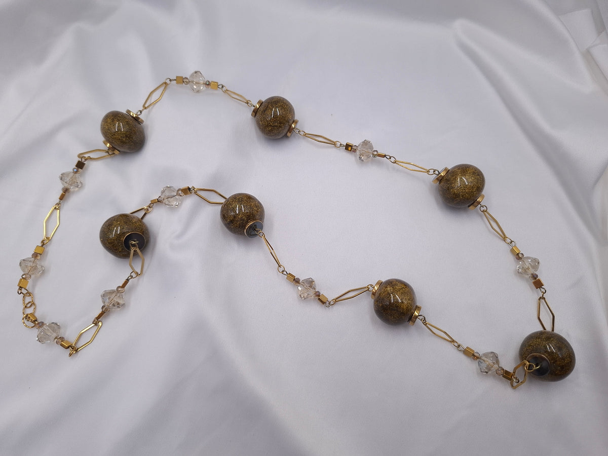 Χειροποίητο μακρύ κολιέ euhandmade με λαδί κεραμικές χάντρες 22mm με χρυσό γκλίτερ, διάφανα κρύσταλλα και χρυσαφί ατσάλινη αλυσίδα.